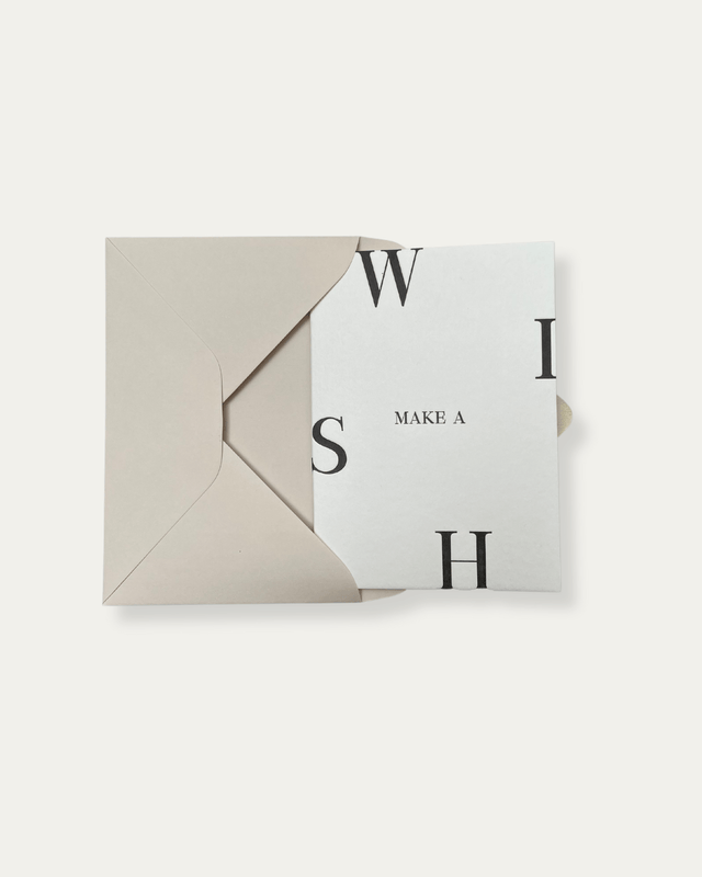 White greeting card with black letterpressed text reading 'Make a Wish' with a beige envelope.