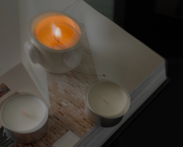 Ceramic tealight holder on an open coffee table book with tealight candles scattered around it.