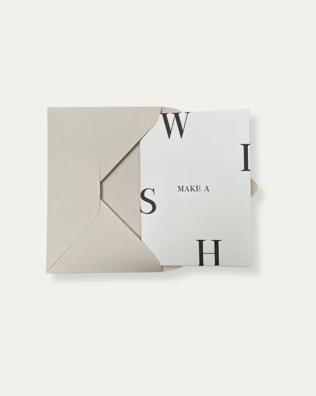 White greeting card with black letterpressed text reading 'Make a Wish' with a beige envelope.